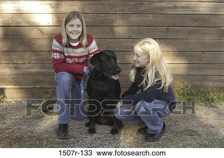 Stock Image - Two girls with a dog. Fotosearch