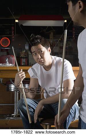 Two men in jeans and t-shirts holding cue sticks View Large Photo Image Stock Image - Two men in jeans and t-shirts holding cue sticks. Fotosearch