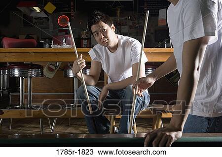 Two men in jeans and t-shirts holding cue sticks View Large Photo Image Stock Image - Two men in jeans and t-shirts holding cue sticks. Fotosearch
