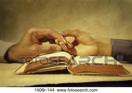 Two people holding hands over an open book View Large Photo Image Picture - Two people holding hands over an open book. Fotosearch