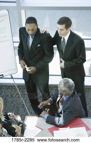 Two young businessmen giving presentation to executives View Large Photo Image Stock Photography - Two young businessmen giving presentation to executives. Fotosearch