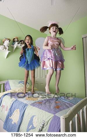 Two young girls in costumes jumping on bed View Large Photo Image Picture - Two young girls in costumes jumping on bed. Fotosearch