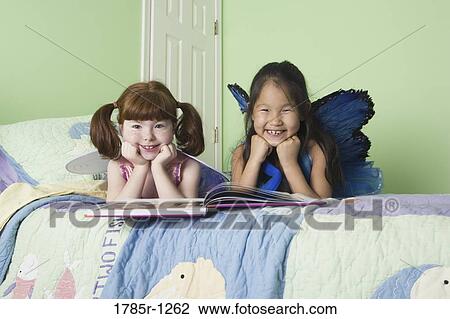 Two young girls in costumes on bed View Large Photo Image Stock Image - Two young girls in costumes on bed. Fotosearch