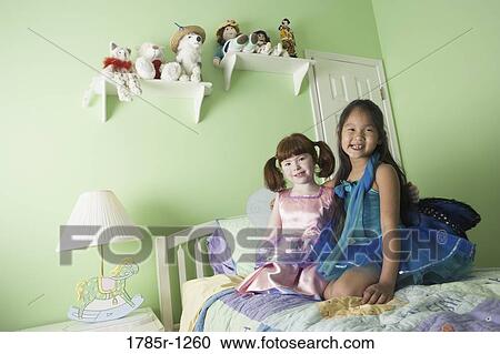 Two young girls in costumes sitting on bed View Large Photo Image Stock Image - Two young girls in costumes sitting on bed. Fotosearch