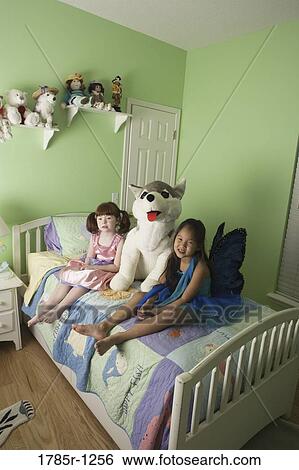 Two young girls in costumes sitting on bed with large stuffed animal View Large Photo Image Stock Photograph - Two young girls in costumes sitting on bed with large stuffed animal. Fotosearch
