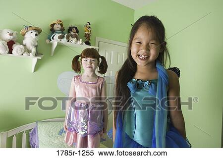 Stock Photography - Two young girls in costumes standing on bed. Fotosearch