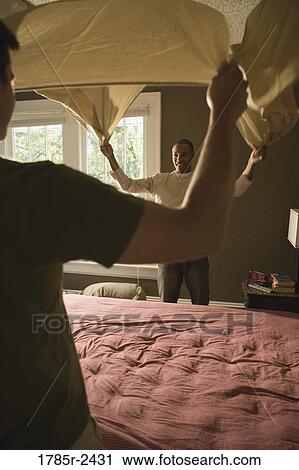 Two young men arranging a bed View Large Photo Image Stock Image - Two young men arranging a bed. Fotosearch