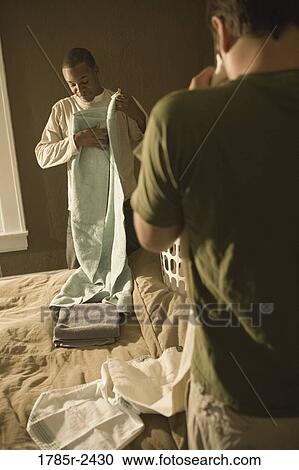 Two young men folding laundry View Large Photo Image Stock Image - Two young men folding laundry. Fotosearch