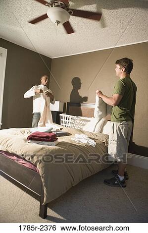 Two young men folding laundry View Large Photo Image Stock Photograph - Two young men folding laundry. Fotosearch