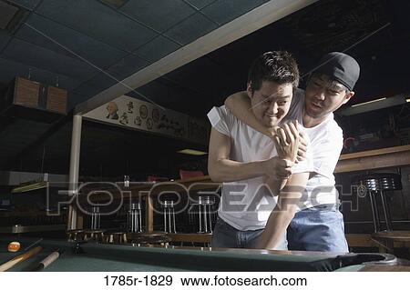Stock Photo - Two young men in jeans and t-shirts fighting in billiards room. Fotosearch