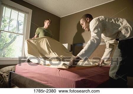 Two young men making a bed View Large Photo Image Stock Image - Two young men making a bed. Fotosearch