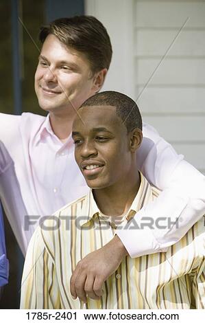 Two young men standing together View Large Photo Image Stock Image - Two young men standing together. Fotosearch