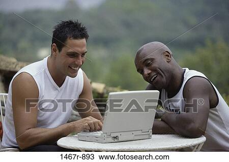 Stock Image - Two young men working on a laptop. Fotosearch