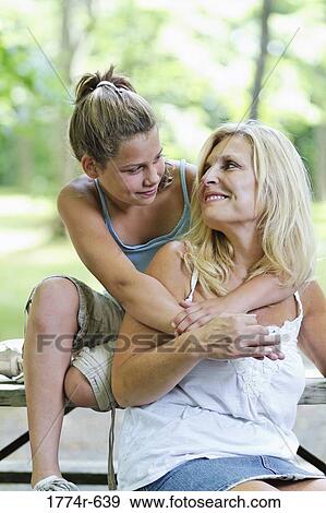 USA, New Jersey, Westfield, Mother and daughter sitting on bench in park, hugging and looking at each other View Large Photo Image Stock Photo - USA, New Jersey, Westfield, Mother and daughter sitting on bench in park, hugging and looking at each other. Fotosearch
