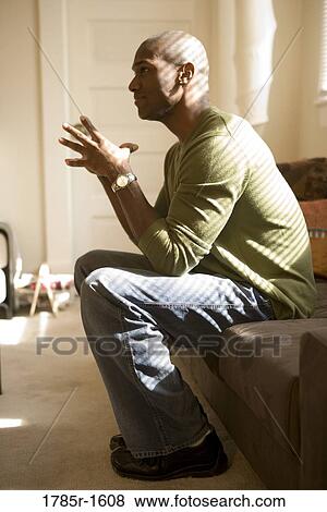 View of a nervous and contemplative young man sitting on sofa View Large Photo Image Stock Photo - View of a nervous and contemplative young man sitting on sofa. Fotosearch