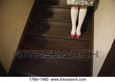 Stock Image - View of a young Asian woman at bottom of staircase. Fotosearch