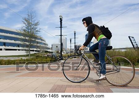 View of a young Asian woman riding a bicycle View Large Photo Image Stock Photography - View of a young Asian woman riding a bicycle. Fotosearch
