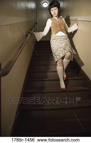 Stock Photograph - View of a young Asian woman walking down the stairs. Fotosearch