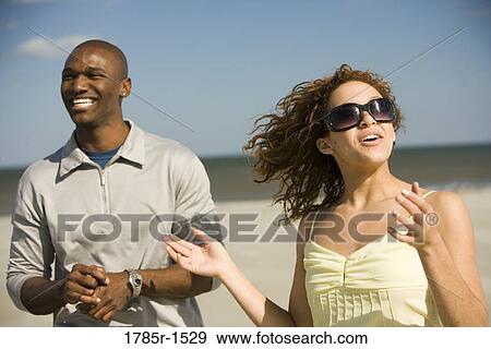 Stock Photo - View of a young couple enjoying themselves on a beach. Fotosearch