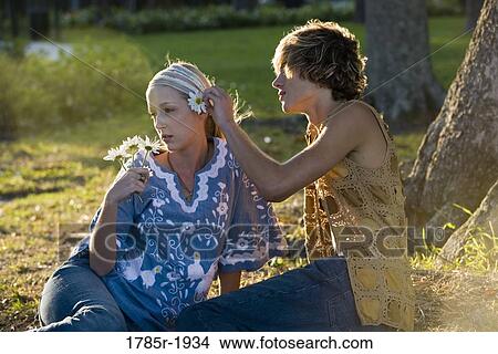 Picture - View of a young couple in vintage 1960's hippie, putting flower behind ear. Fotosearch