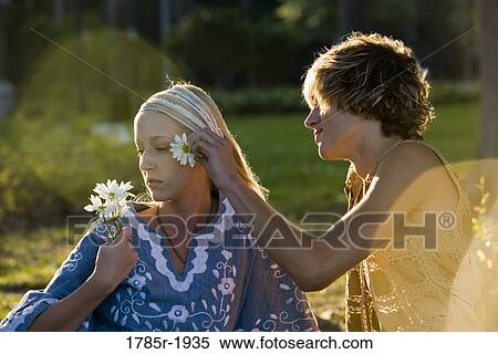 Stock Photography - View of a young couple in vintage 1960's hippie, putting flower behind ear. Fotosearch