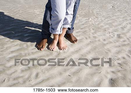 View of the legs and feet of a romantic young couple standing on beach View Large Photo Image Stock Image - View of the legs and feet of a romantic young couple standing on beach. Fotosearch