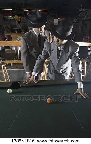 View of two men in suits and hats standing beside billiards table and talking View Large Photo Image Stock Photograph - View of two men in suits and hats standing beside billiards table and talking. Fotosearch