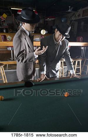 View of two men in suits and hats standing beside billiards table and talking View Large Photo Image Stock Photography - View of two men in suits and hats standing beside billiards table and talking. Fotosearch