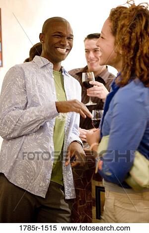 View of young couple socializing in a crowded bar while holding wineglasses View Large Photo Image Stock Photography - View of young couple socializing in a crowded bar while holding wineglasses. Fotosearch