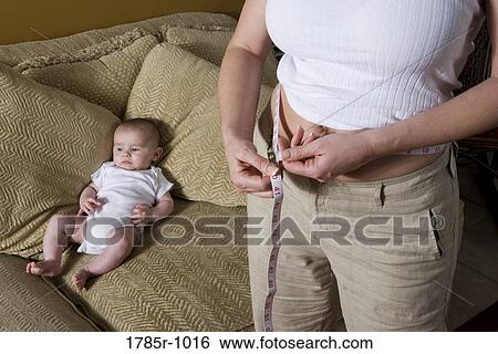 Stock Photograph - Woman measuring weight loss after pregnancy. Fotosearch
