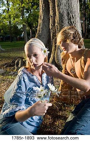 Young affectionate hippie couple relaxing under tree View Large Photo Image Stock Image - Young affectionate hippie couple relaxing under tree. Fotosearch