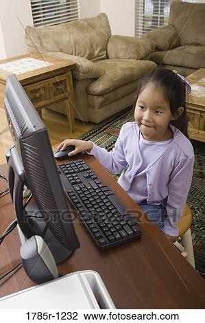 Stock Image - Young Asian girl using computer. Fotosearch