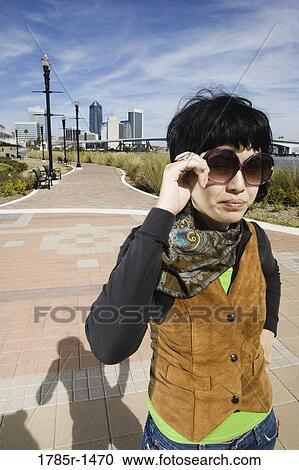Young Asian woman adjusting her sunglasses View Large Photo Image Stock Image - Young Asian woman adjusting her sunglasses. Fotosearch