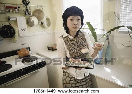 Young Asian woman eating sushi in kitchen View Large Photo Image Stock Photo - Young Asian woman eating sushi in kitchen. Fotosearch