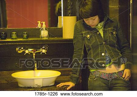 Stock Photograph - Young Asian woman in washroom. Fotosearch
