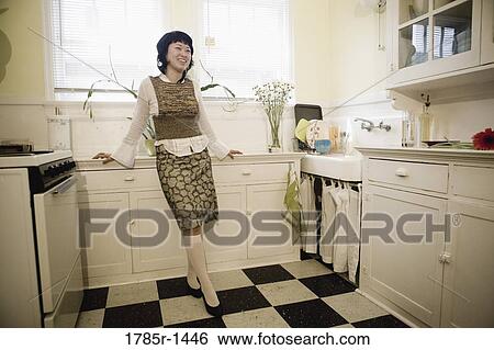 Young Asian woman leaning against countertop in apartment kitchen View Large Photo Image Stock Photograph - Young Asian woman leaning against countertop in apartment kitchen. Fotosearch