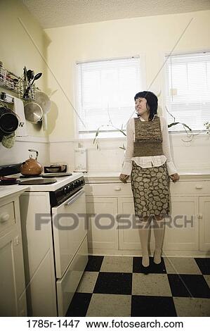 Young Asian woman sitting on kitchen counter View Large Photo Image Stock Photo - Young Asian woman sitting on kitchen counter. Fotosearch