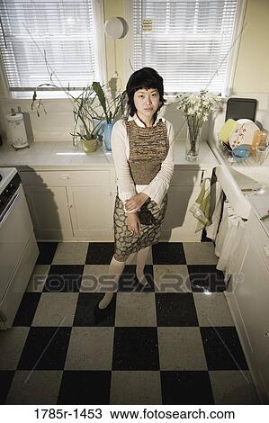 Young Asian woman standing in kitchen View Large Photo Image Stock Image - Young Asian woman standing in kitchen. Fotosearch
