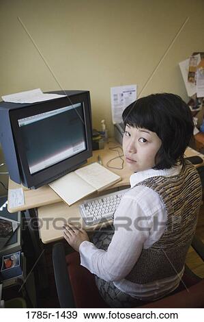 Young Asian woman working on computer at desk View Large Photo Image Stock Photo - Young Asian woman working on computer at desk. Fotosearch