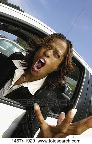 Stock Photo - Young businesswoman screaming from inside a car. Fotosearch