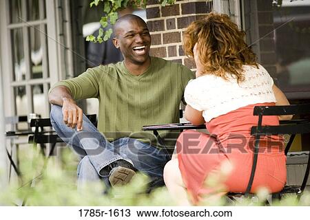 Young couple sitting at a table at a sidewalk cafÄ View Large Photo Image Stock Image - Young couple sitting at a table at a sidewalk cafÄ. Fotosearch