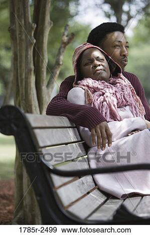 Stock Photo - Young couple sitting on a bench. Fotosearch
