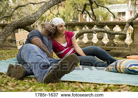 Young couple sitting on a picnic blanket in a garden View Large Photo Image Stock Photo - Young couple sitting on a picnic blanket in a garden. Fotosearch