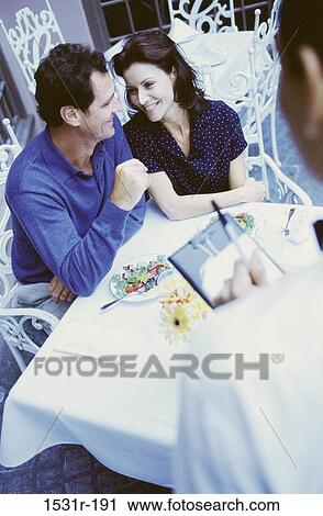 Stock Image - Young couple sitting together at a restaurant. Fotosearch