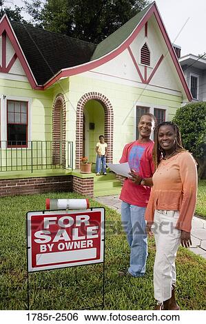 Young couple standing outside house by For Sale sign View Large Photo Image Stock Photograph - Young couple standing outside house by For Sale sign. Fotosearch
