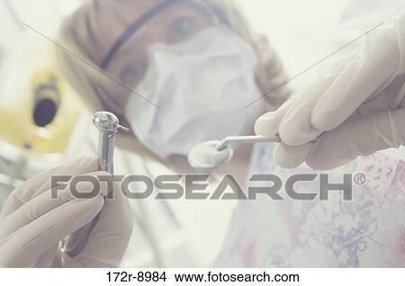 Young female dentist holding a drill View Large Photo Image Picture - Young female dentist holding a drill. Fotosearch