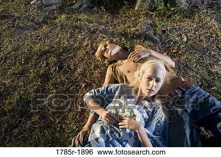 Stock Photograph - Young hippie couple lying on the ground. Fotosearch