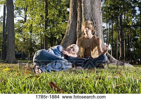 Young hippie couple relaxing and meditating under tree View Large Photo Image Picture - Young hippie couple relaxing and meditating under tree. Fotosearch