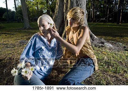 Stock Image - Young hippie couple relaxing under tree. Fotosearch