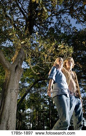 Stock Photo - Young hippie couple standing under tree. Fotosearch